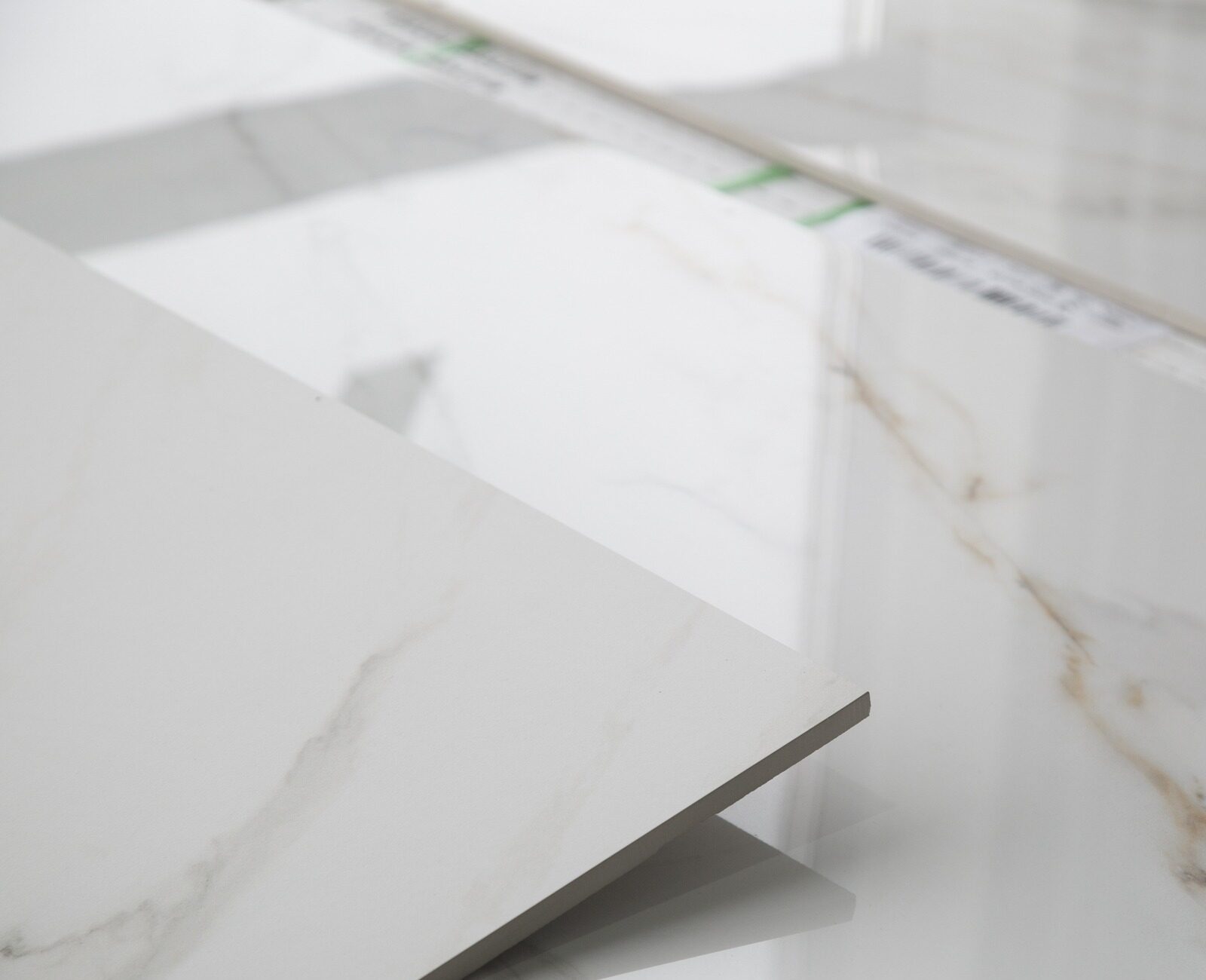 Several large, smooth, polished white marble tiles with subtle brown veining are displayed on a clean surface, creating a sleek, modern appearance.